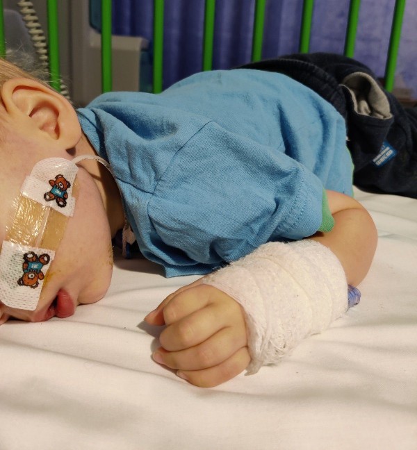 Laura Fanthorpe's son, Arthur, in a hospital bed with a tube taped to his face and bandages on his hand.  (Image: Laura Fanthorpe)